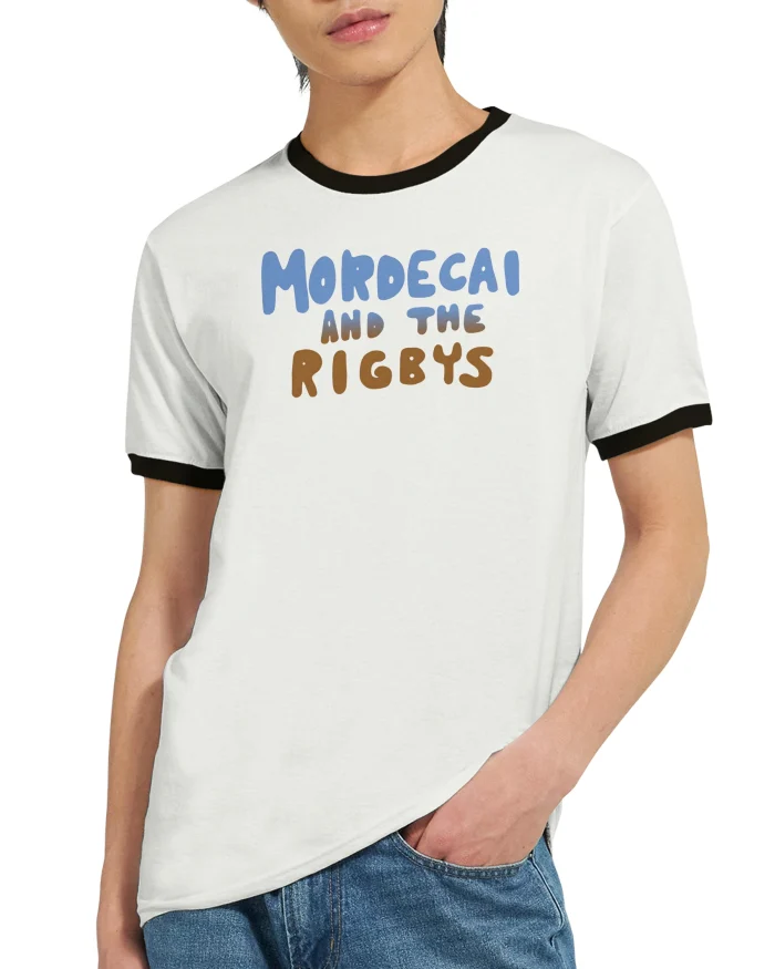 A person stands with one hand in their pocket, wearing the Mordecai and the Rigbys Shirt—a white ringer tee with black trim and blue and brown text reading "Mordecai and the Rigbys.