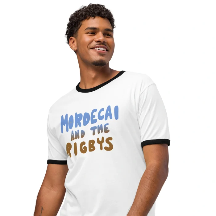 A smiling man wears the Mordecai and the Rigbys Shirt, a white ringer tee with black trim and the band's name printed in blue and brown across the chest.