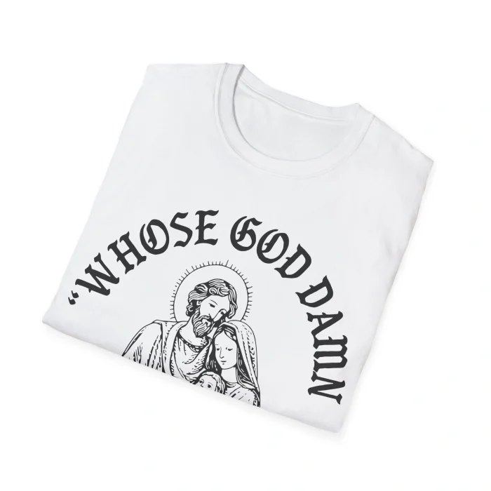 A folded white "Whose God Damn White Baby Is This Shirt" featuring a black line drawing of two religious figures and bold, arched “WHOSE GOD DAMN” text above and below the illustration.